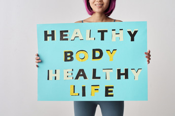 a woman is holding up a sign that says "Healthy Body, Healthy Life"